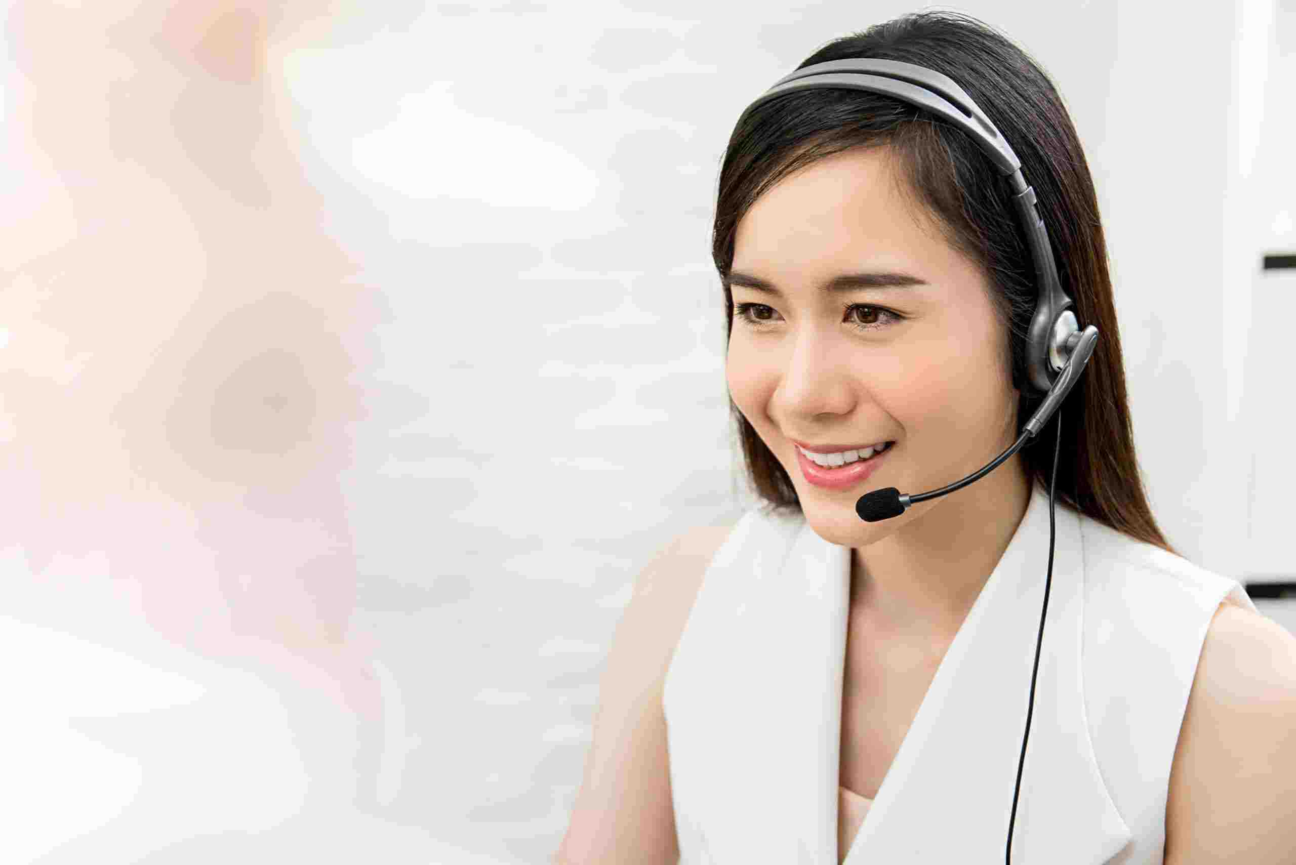 Asian woman wearing a headset and a white dress.