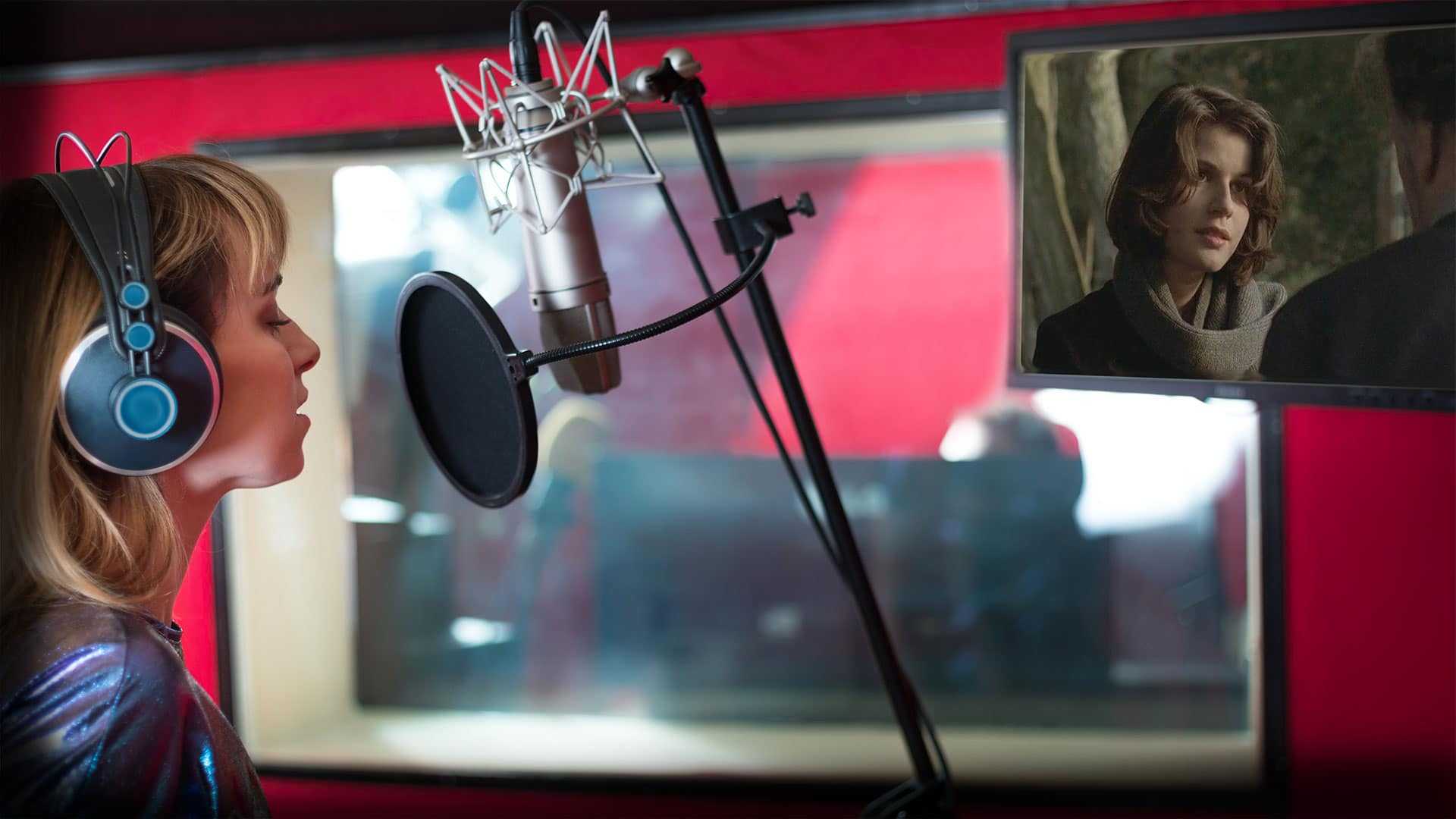 Woman talking into a microphone in a studio.