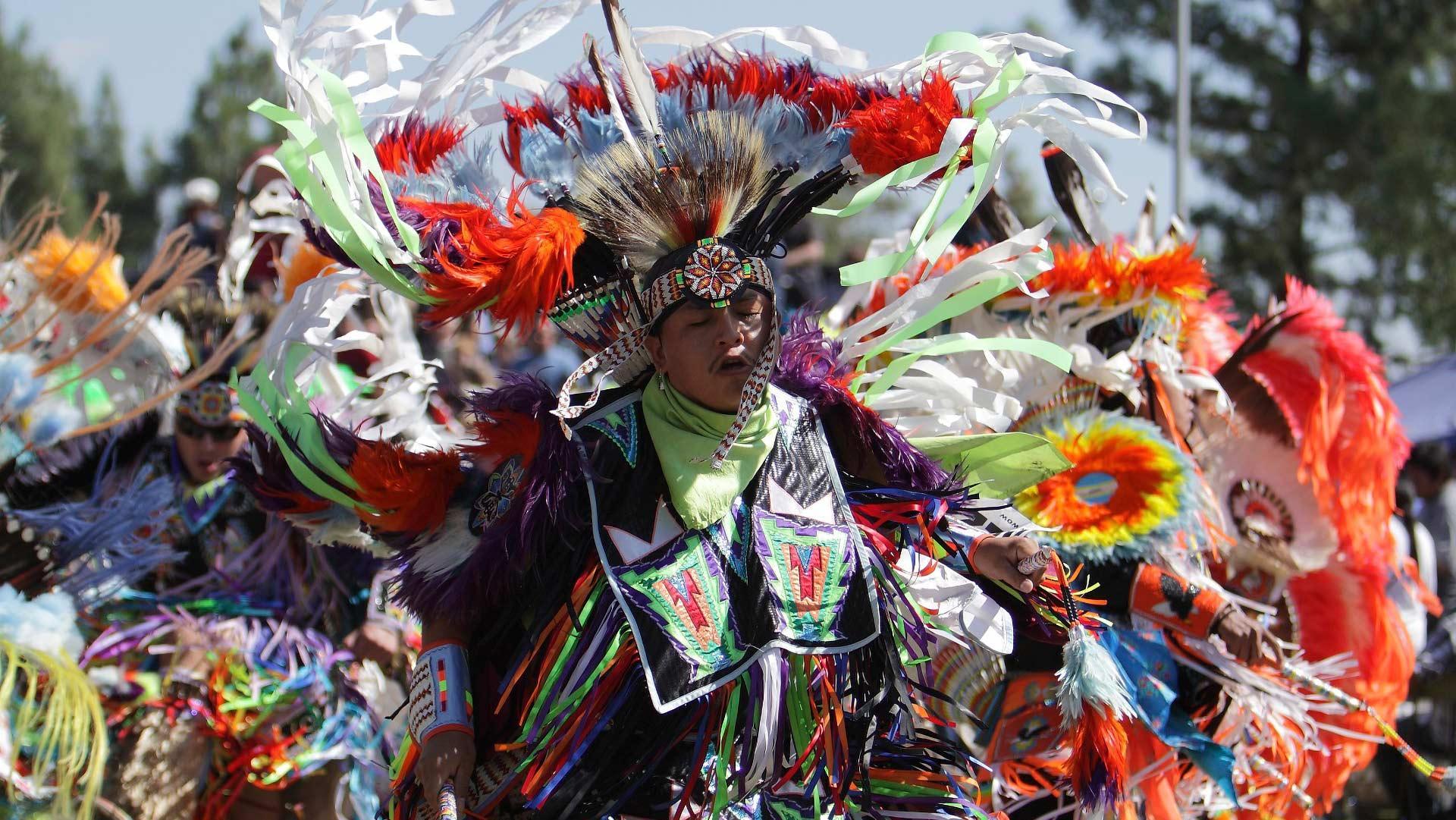 A man dancing in a full Sioux tribal outfit.